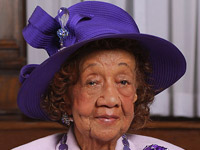 Dorothy Height styling in a purple dress and royal purple hat