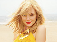 Emma Stone on the beach posing in a sunshine yellow dress for an Elle photo shoot.